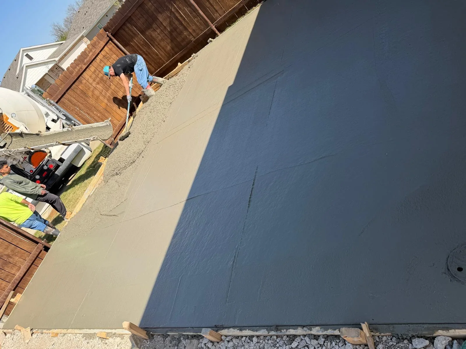 Worker finishing freshly poured concrete driveway with broom finish technique