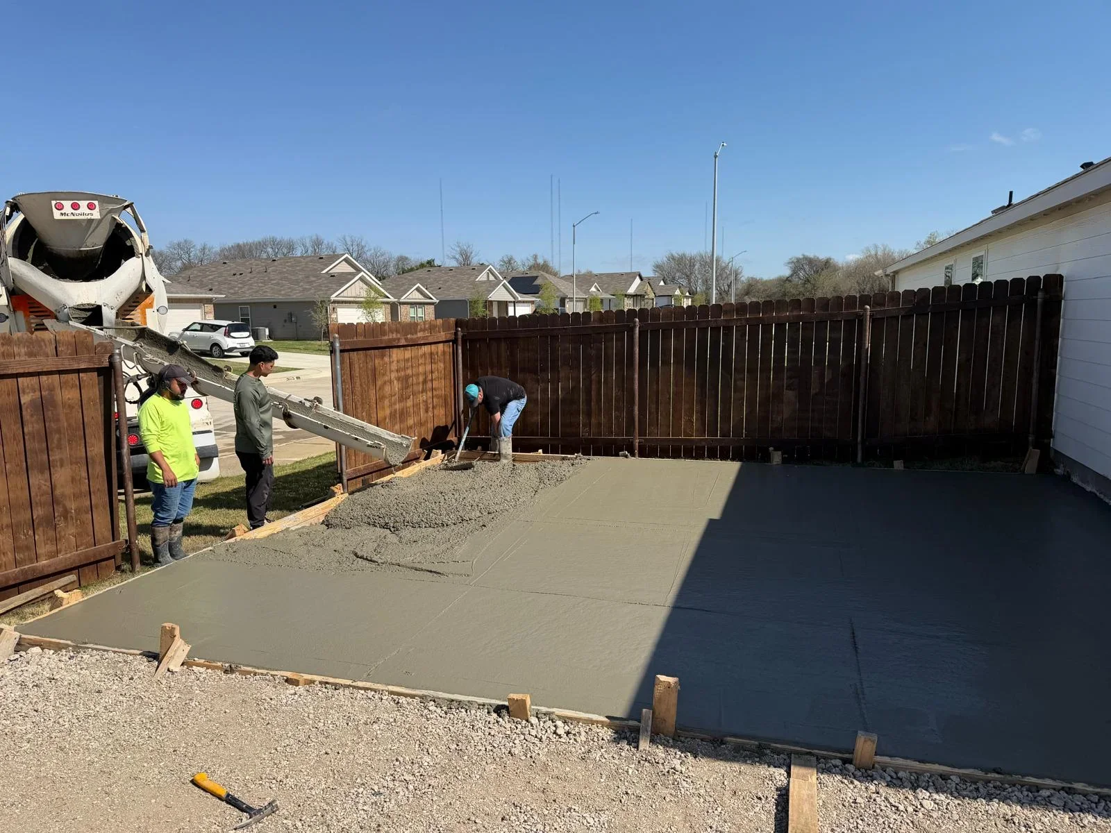 Concrete crew pouring and finishing residential driveway with gravel base and wooden forms