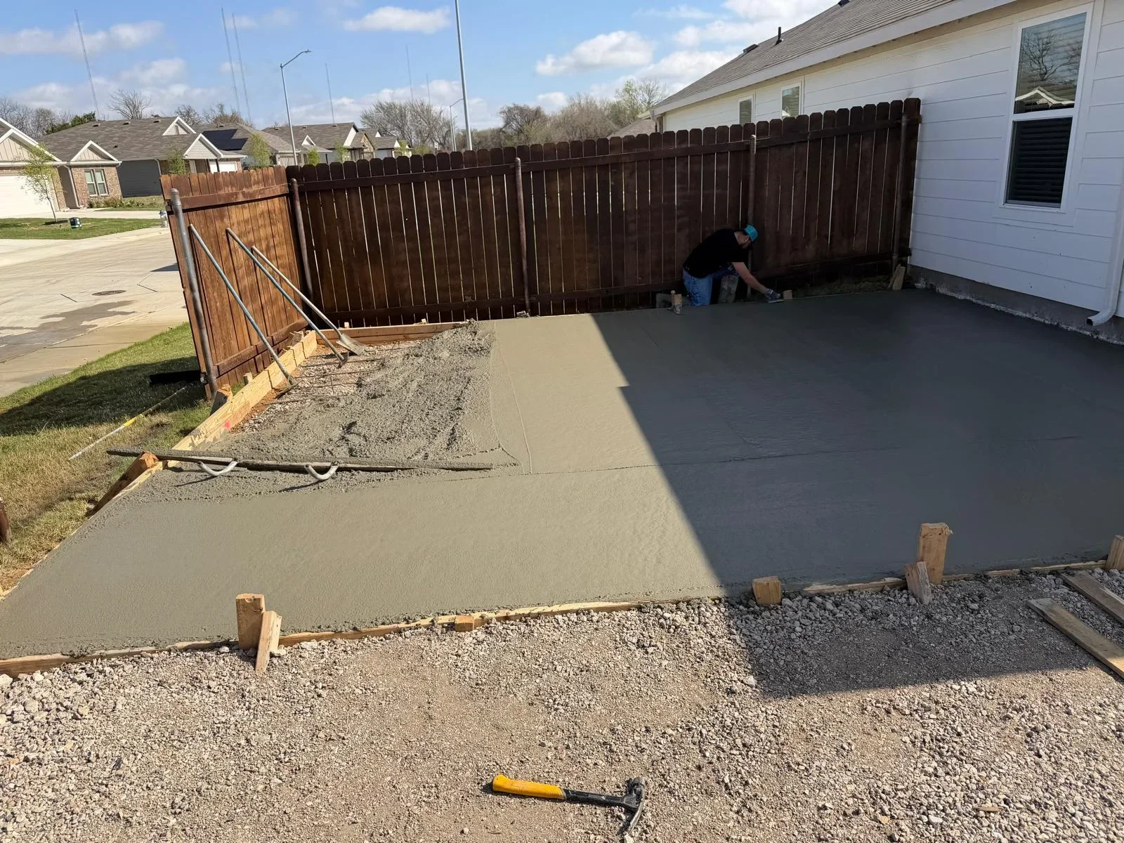 Fresh concrete patio pour in progress with wooden forms and gravel base visible