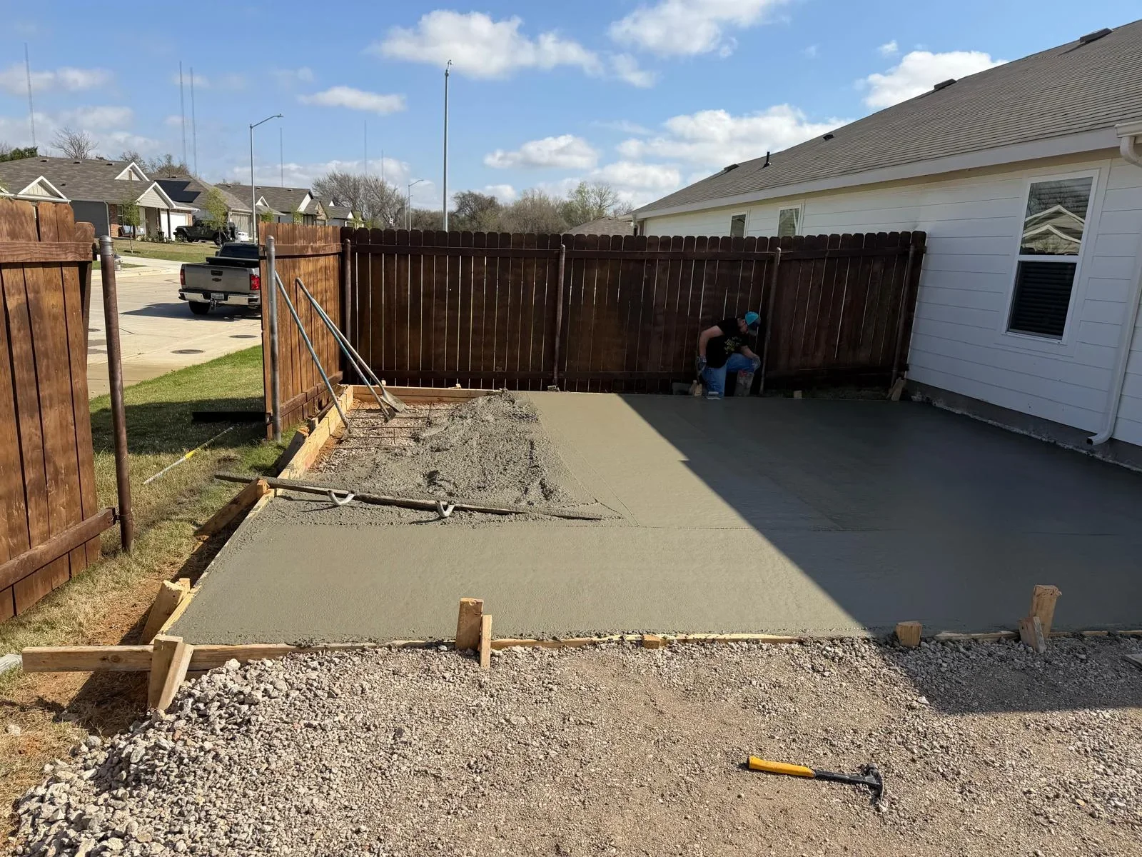 Freshly poured concrete patio with wooden forms and gravel base in residential backyard