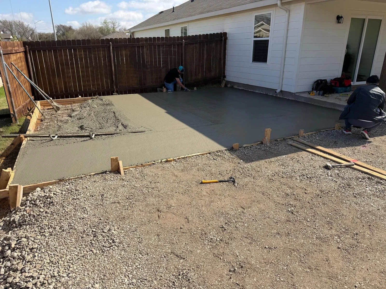 Fresh concrete patio pour in progress with wooden forms and gravel base in residential backyard