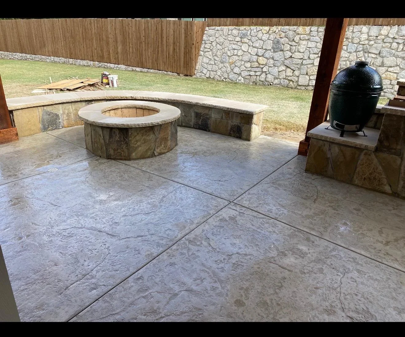 Stamped concrete patio with circular fire pit, built-in seating, and stone accents