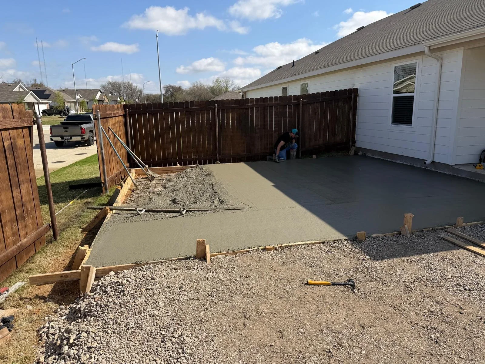 Concrete patio pour in progress with wooden forms and gravel base in residential backyard